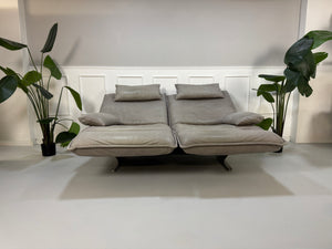 Gebrauchtes graues Ledersofa Koinor Modell Evia vor einer modernen Wand.