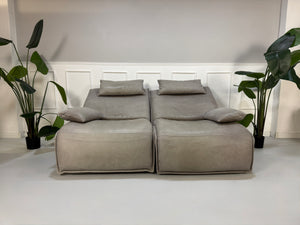 Gebrauchtes graues Ledersofa Koinor Modell Evia vor einer modernen Wand.