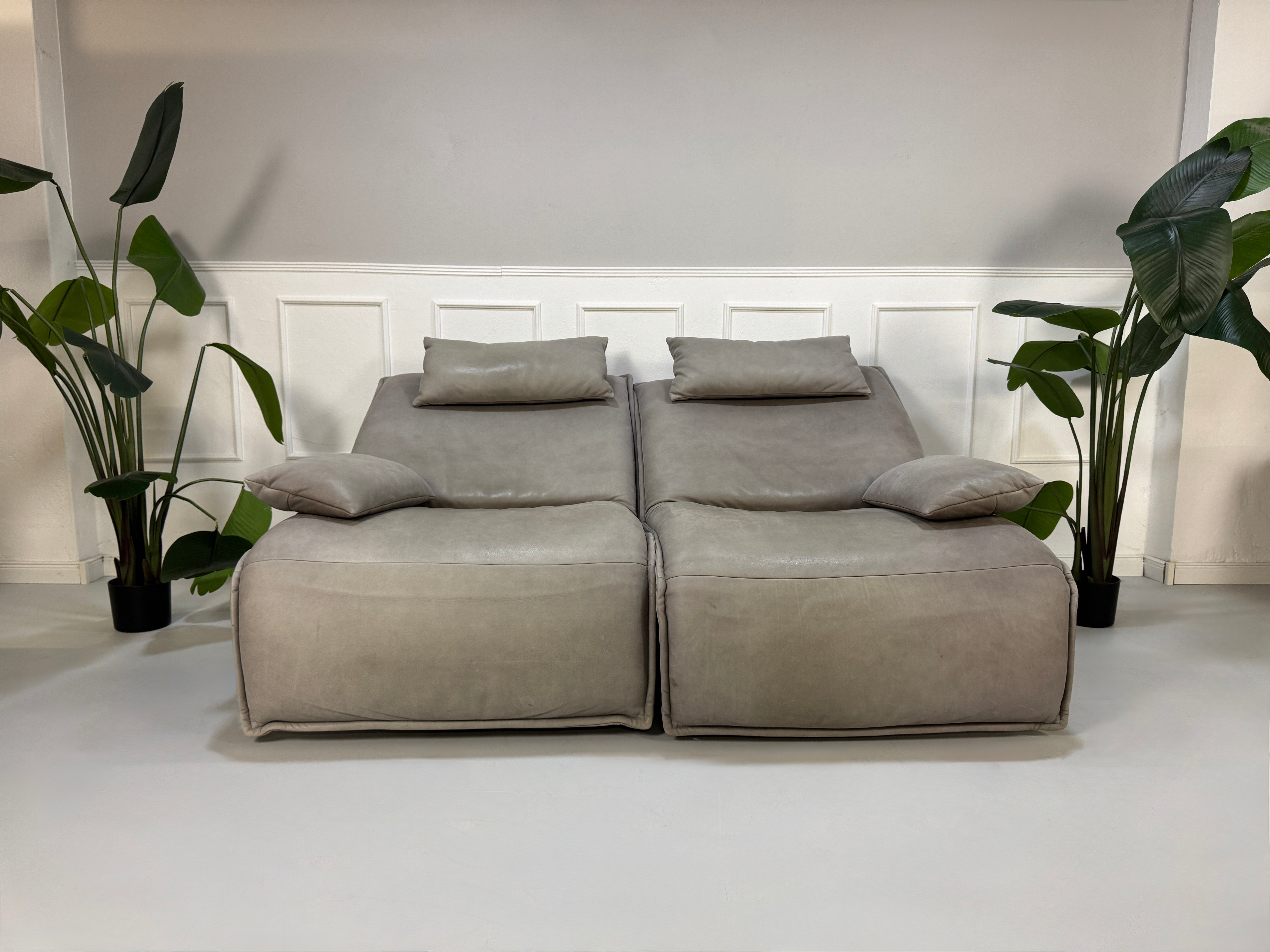Gebrauchtes graues Ledersofa Koinor Modell Evia vor einer modernen Wand.