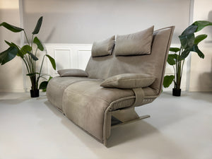 Gebrauchtes graues Ledersofa Koinor Modell Evia vor einer modernen Wand.