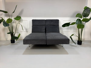 Gebrauchtes graues Stoffsofa Brühl Modell Moule Small vor einer modernen Wand