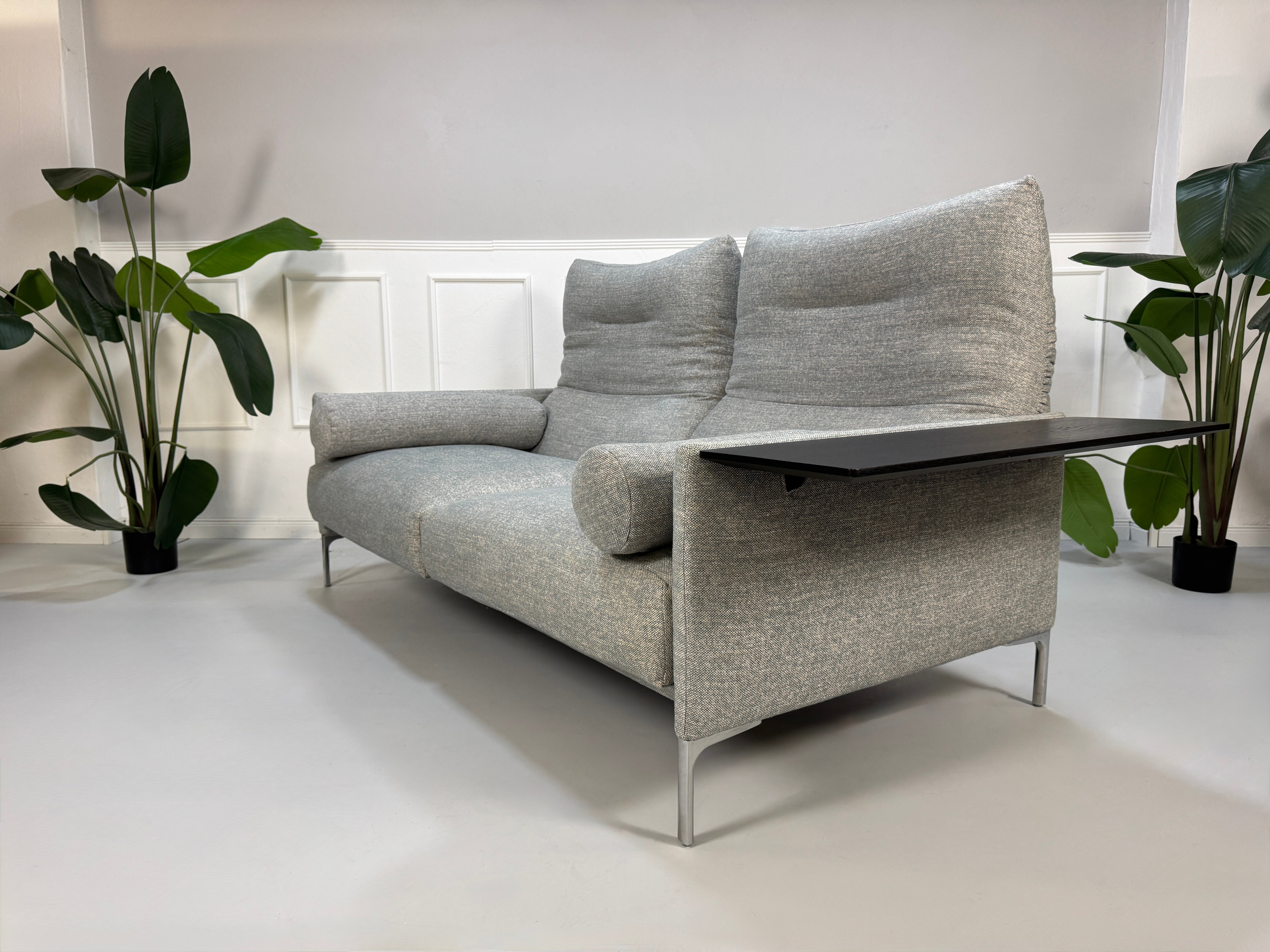 Gebrauchtes graues Stoffsofa mit einem Hocker von COR Modell Avalanche vor einer modernen Wand.