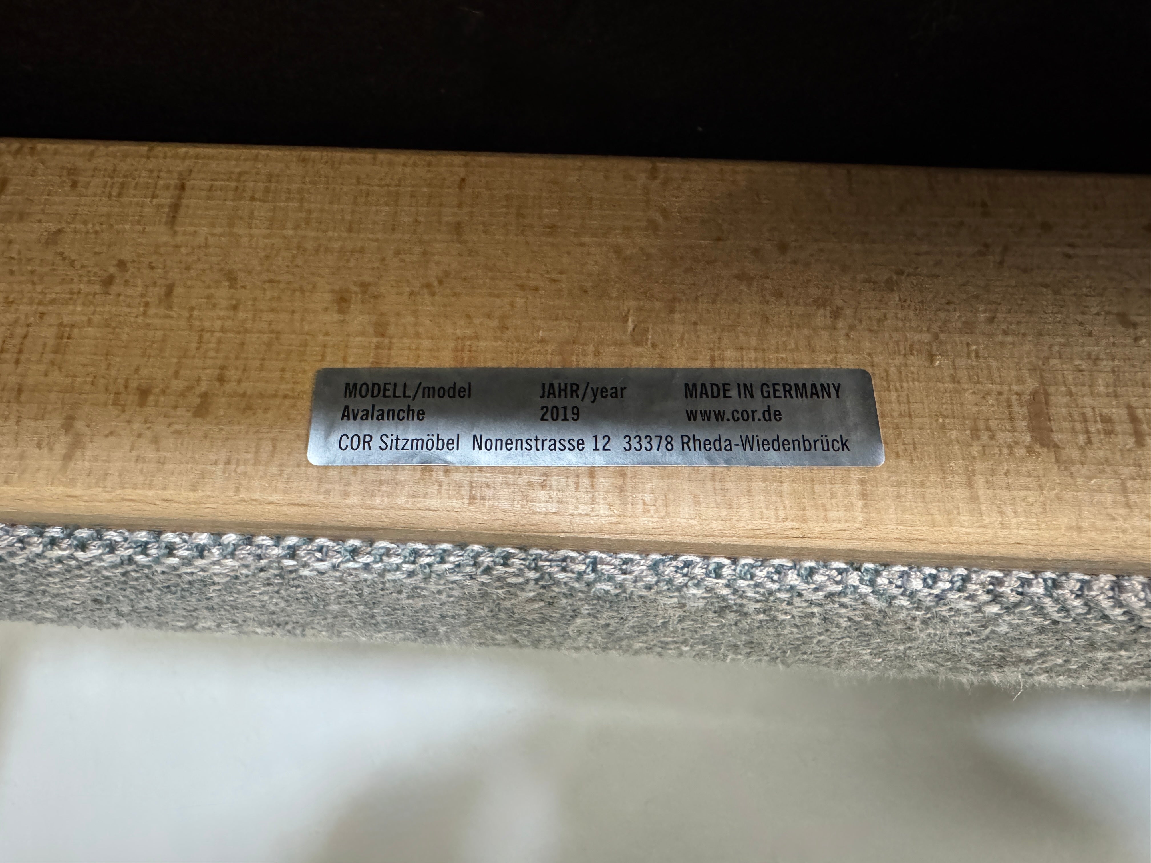 Gebrauchtes graues Stoffsofa mit einem Hocker von COR Modell Avalanche vor einer modernen Wand.