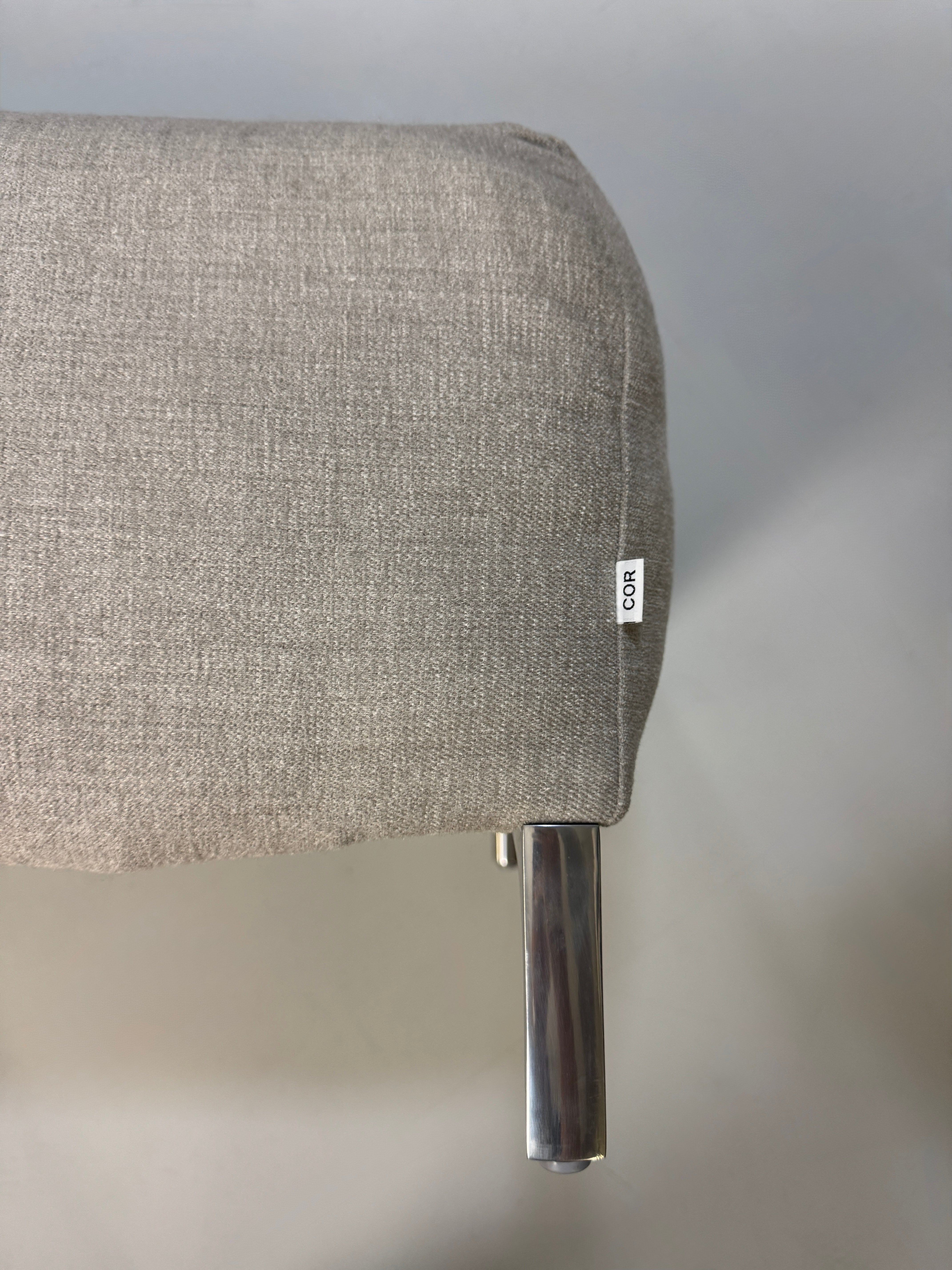 Gebrauchtes graues Stoffsofa mit einem Hocker von COR Modell Avalanche vor einer modernen Wand.