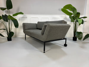 Gebrauchtes graues Stoffsofa Brühl Modell Roro Soft vor einer modernen Wand.