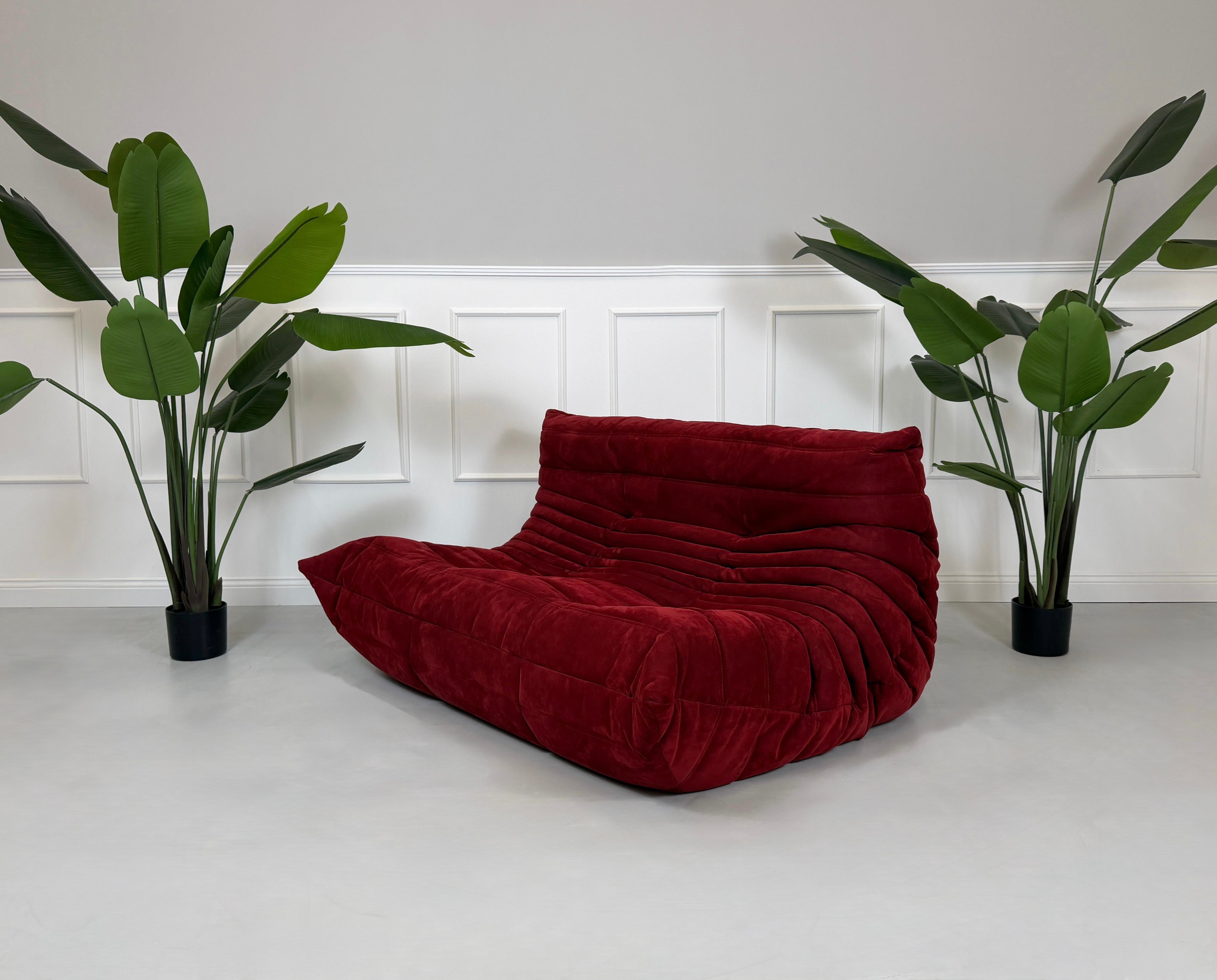 Gebrauchtes rotes Stoffsofa Ligne Roset Modell Togo vor einer modernen Wand.