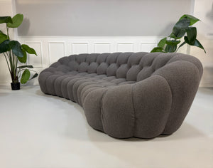 Gebrauchtes graues Stoffsofa Roche Bobois Modell Bubble vor einer modernen Wand.