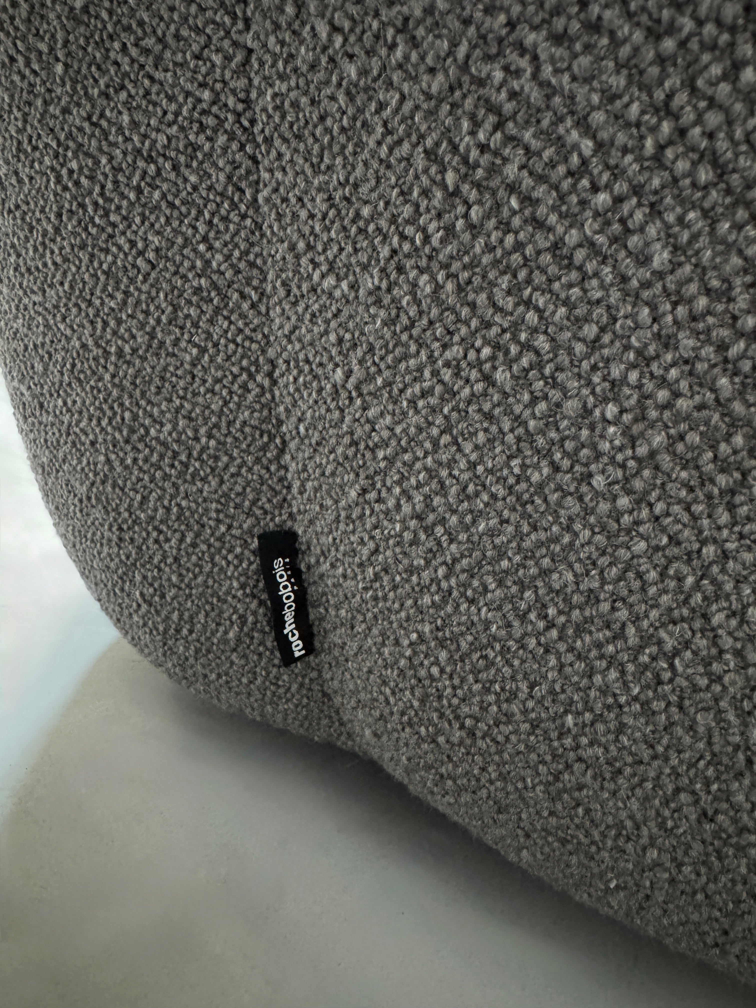 Gebrauchtes graues Stoffsofa Roche Bobois Modell Bubble vor einer modernen Wand.
