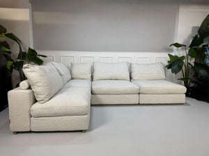 Gebrauchtes weißes Stoffsofa Flexform Modell Groundpiece vor einer modernen Wand.