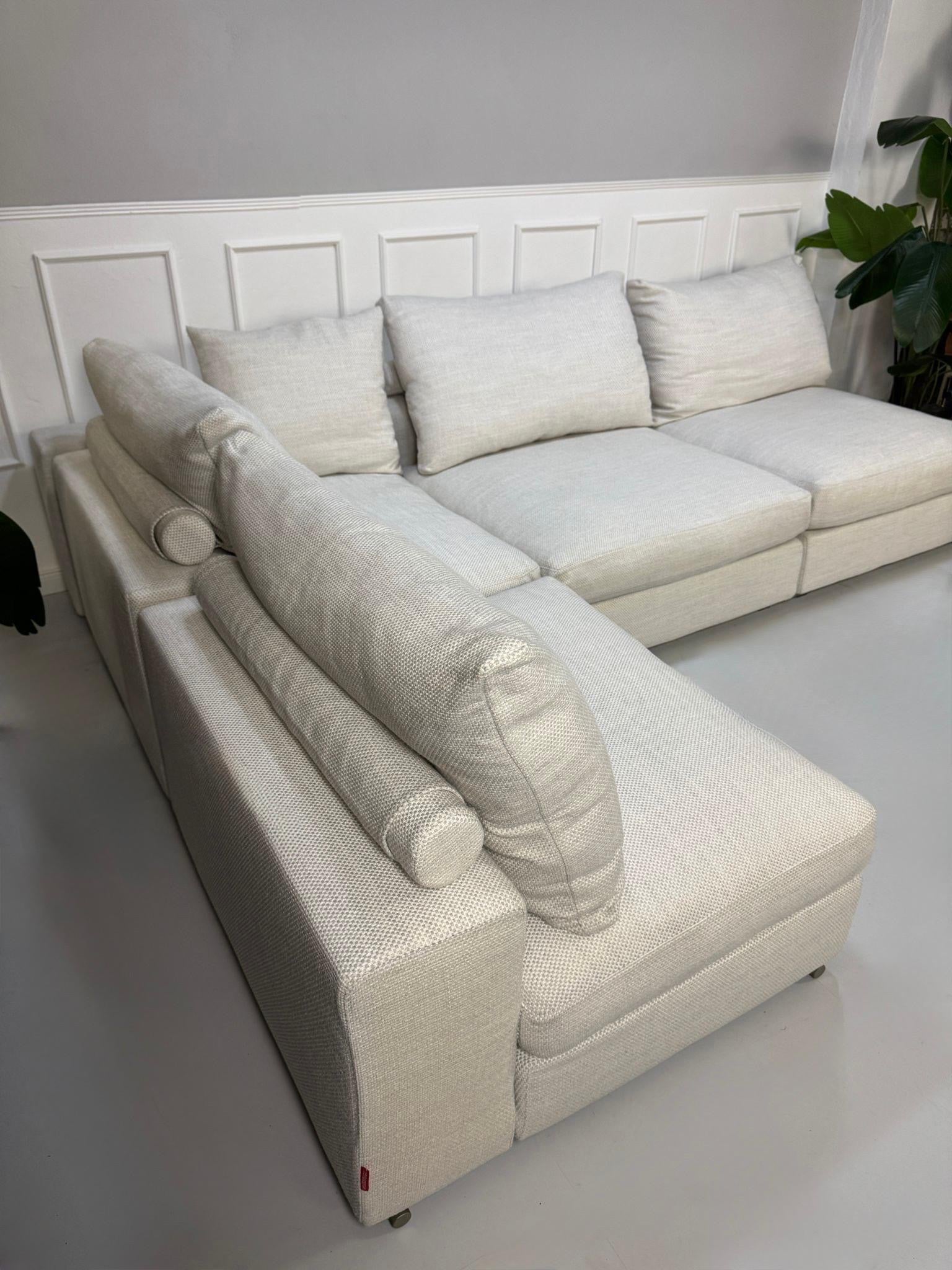 Gebrauchtes weißes Stoffsofa Flexform Modell Groundpiece vor einer modernen Wand.