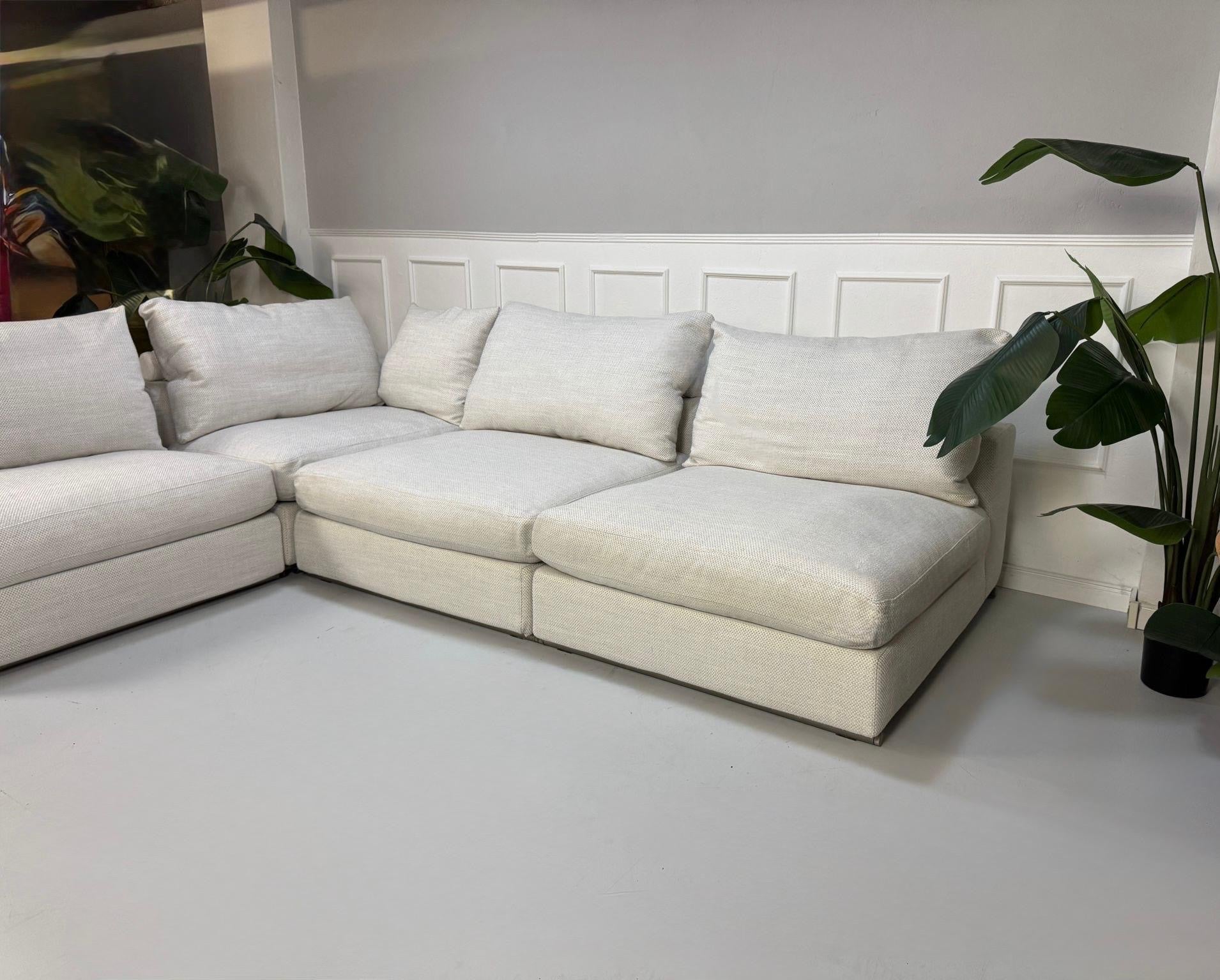 Gebrauchtes weißes Stoffsofa Flexform Modell Groundpiece vor einer modernen Wand.