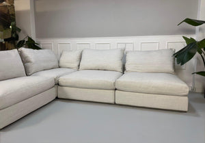 Gebrauchtes weißes Stoffsofa Flexform Modell Groundpiece vor einer modernen Wand.