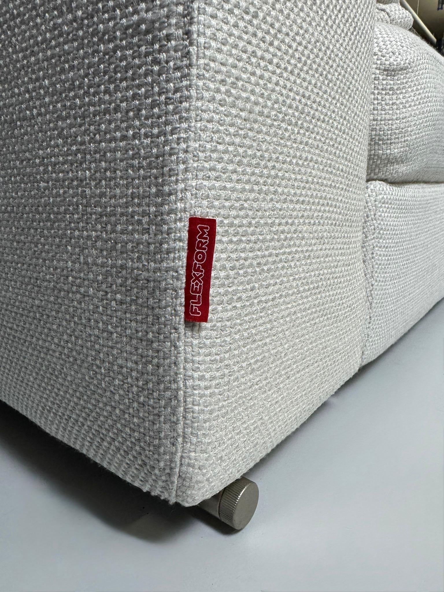Gebrauchtes weißes Stoffsofa Flexform Modell Groundpiece vor einer modernen Wand.