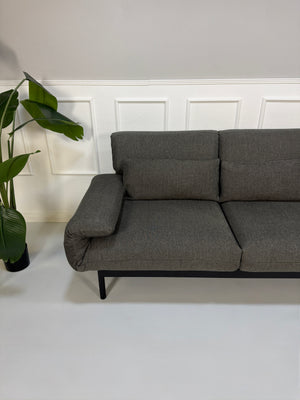Gebrauchtes graues Stoffsofa Rolf Benz Modell Plura vor einer modernen Wand.