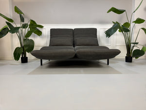 Gebrauchtes graues Stoffsofa Rolf Benz Modell Plura vor einer modernen Wand.