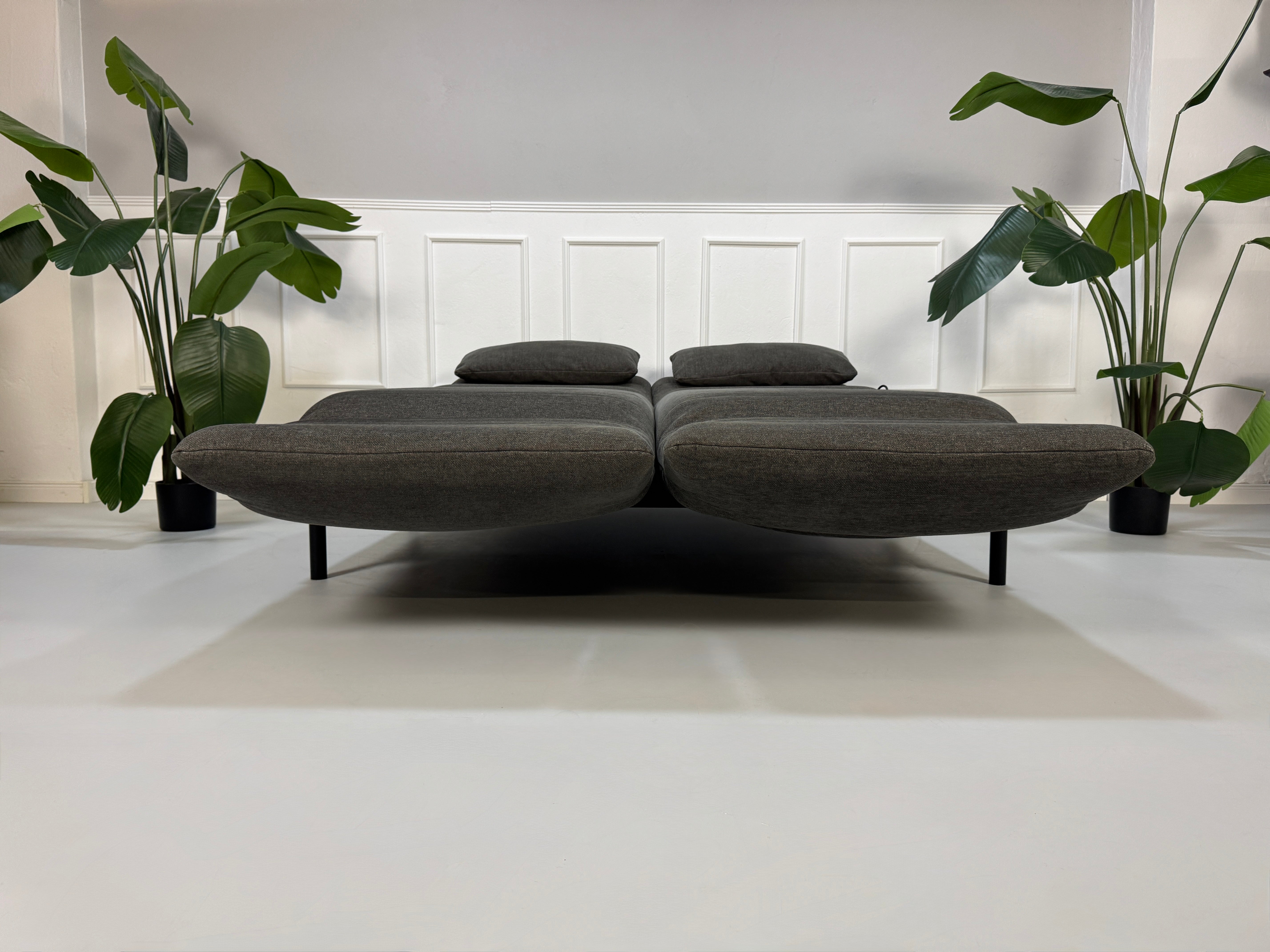 Gebrauchtes graues Stoffsofa Rolf Benz Modell Plura vor einer modernen Wand.