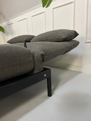 Gebrauchtes graues Stoffsofa Rolf Benz Modell Plura vor einer modernen Wand.