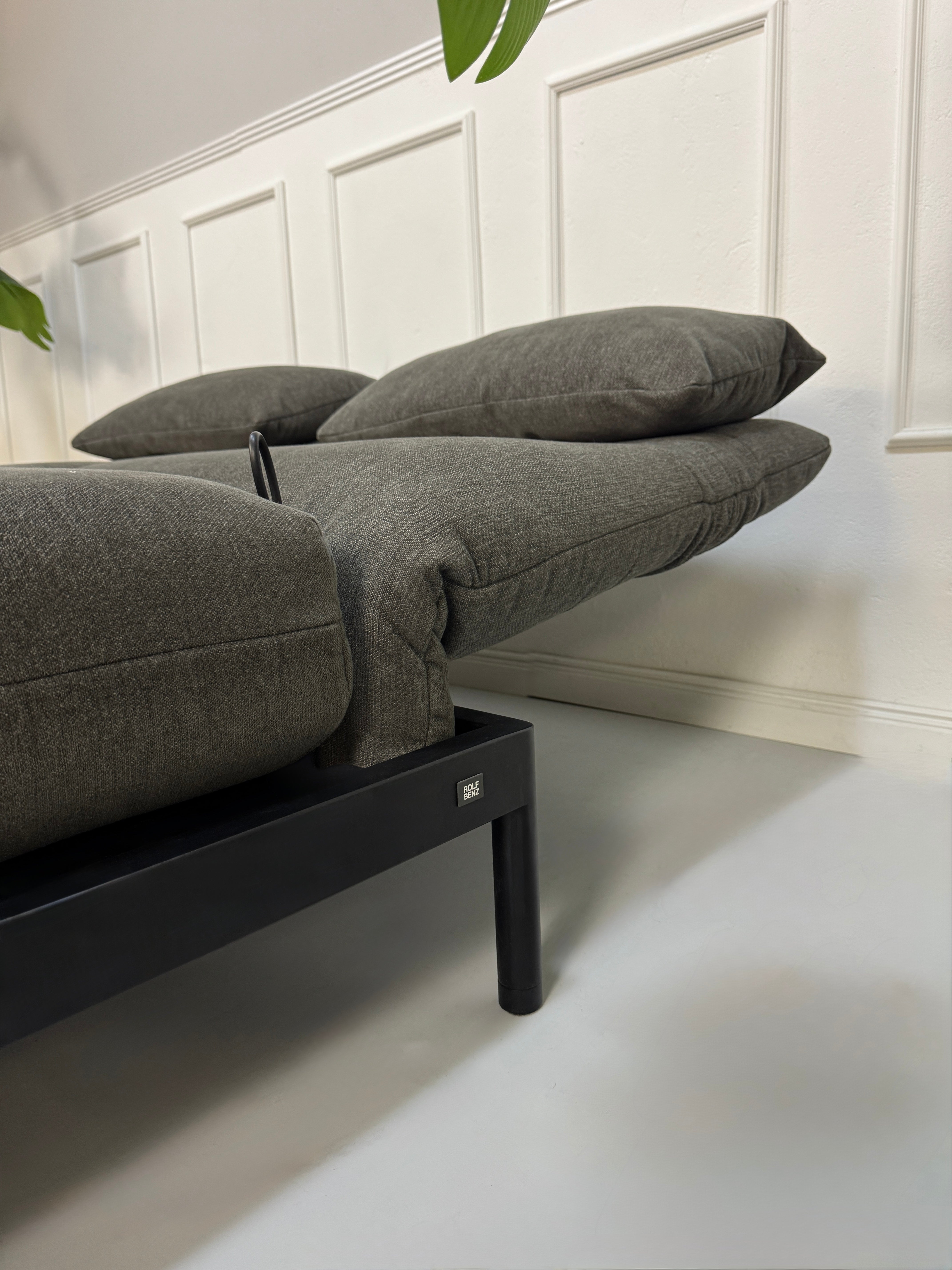 Gebrauchtes graues Stoffsofa Rolf Benz Modell Plura vor einer modernen Wand.