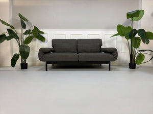 Gebrauchtes graues Stoffsofa Rolf Benz Modell Plura vor einer modernen Wand.