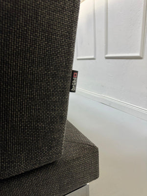 Gebrauchtes graues Stoffsofa Brühl Modell Moule vor einer modernen Wand.