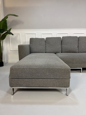 Gebrauchtes graues Brühl Fourtwo Designer Stoff Sofa vor einer Wand, stilvoll und modern eingerichtet.