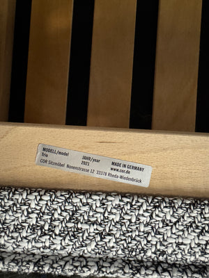 Gebrauchtes graues COR Trio Designer Stoff Sofa vor einer Wand, stilvoll und modern eingerichtet.