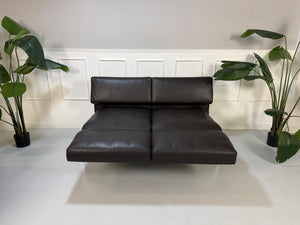 Gebrauchtes braunes Ledersofa Brühl Modell Roro Soft vor einer modernen Wand.