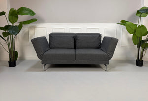 Graues Brühl Moule Ausstellungsstück Designer Stoff Sofa vor einer Wand, stilvoll und modern eingerichtet.