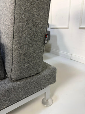 Graues Brühl Moule Ausstellungsstück Designer Stoff Sofa vor einer Wand, stilvoll und modern eingerichtet.