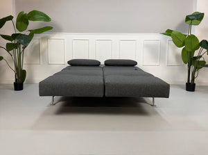 Graues Brühl Moule Ausstellungsstück Designer Stoff Sofa vor einer Wand, stilvoll und modern eingerichtet.