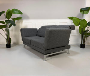 Graues Brühl Moule Ausstellungsstück Designer Stoff Sofa vor einer Wand, stilvoll und modern eingerichtet.