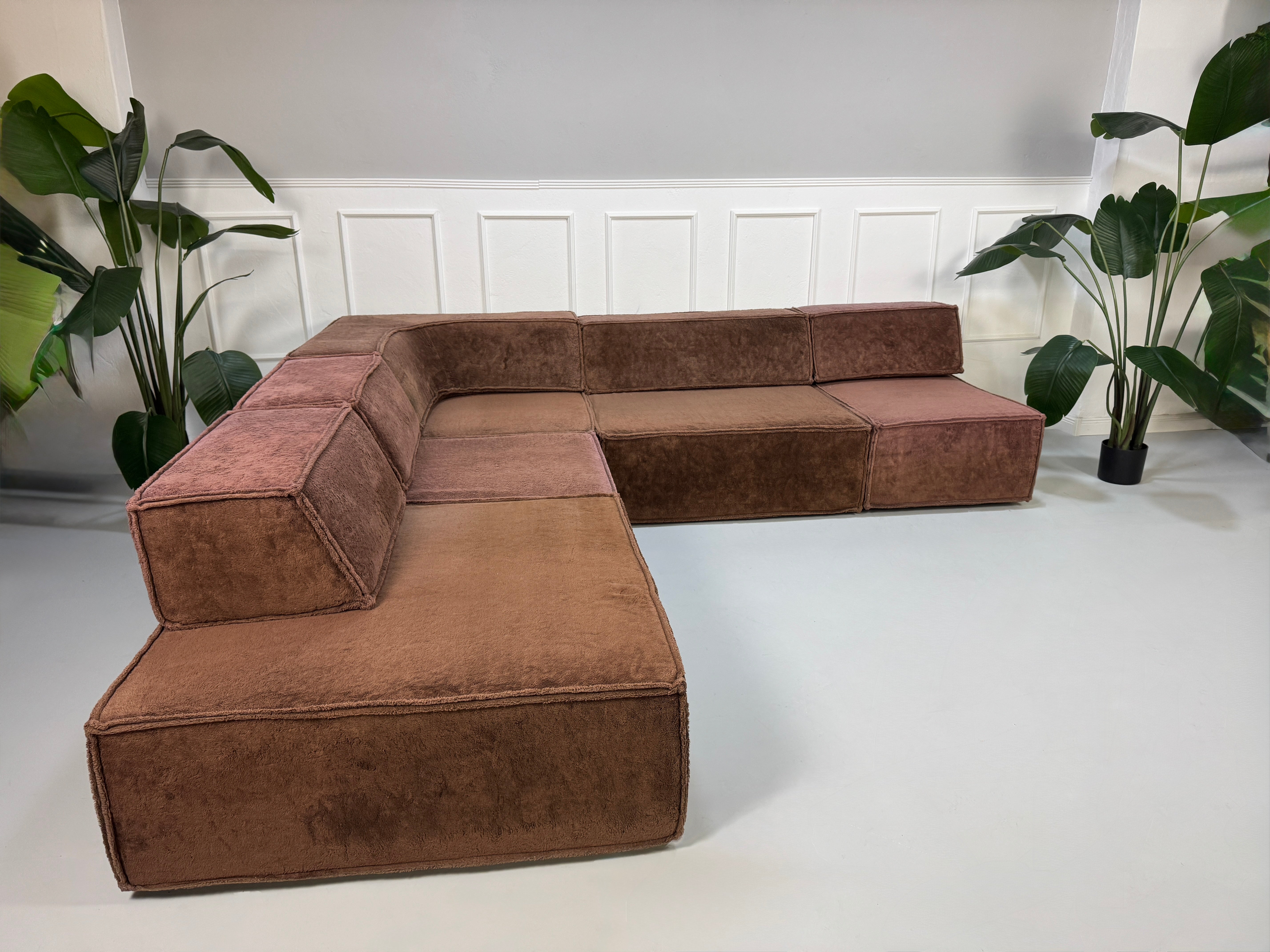 Gebrauchtes modulares braunes COR Trio Designer Stoff Sofa vor einer Wand, stilvoll und modern eingerichtet.