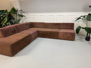Gebrauchtes modulares braunes COR Trio Designer Stoff Sofa vor einer Wand, stilvoll und modern eingerichtet.