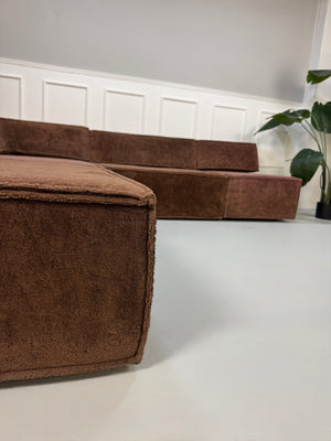 Gebrauchtes modulares braunes COR Trio Designer Stoff Sofa vor einer Wand, stilvoll und modern eingerichtet.