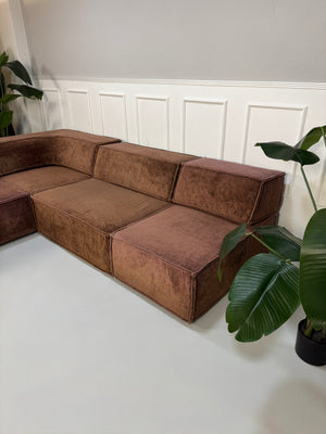Gebrauchtes modulares braunes COR Trio Designer Stoff Sofa vor einer Wand, stilvoll und modern eingerichtet.