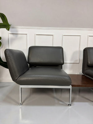 Gebrauchtes graues Brühl Roro Designer Leder Sofa mit Tisch vor einer Wand, stilvoll und modern eingerichtet.