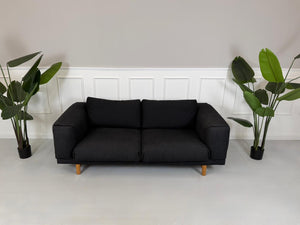 Gebrauchtes Muuto Rest Designer Stoff Sofa in der Farbe Grau vor einer Wand, stilvoll und modern eingerichtet.