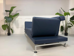 Gebrauchtes Brühl Moule Designer Leder Sofa in der Farbe Blau vor einer Wand, stilvoll und modern eingerichtet.