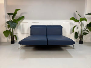 Gebrauchtes Brühl Moule Designer Leder Sofa in der Farbe Blau vor einer Wand, stilvoll und modern eingerichtet.