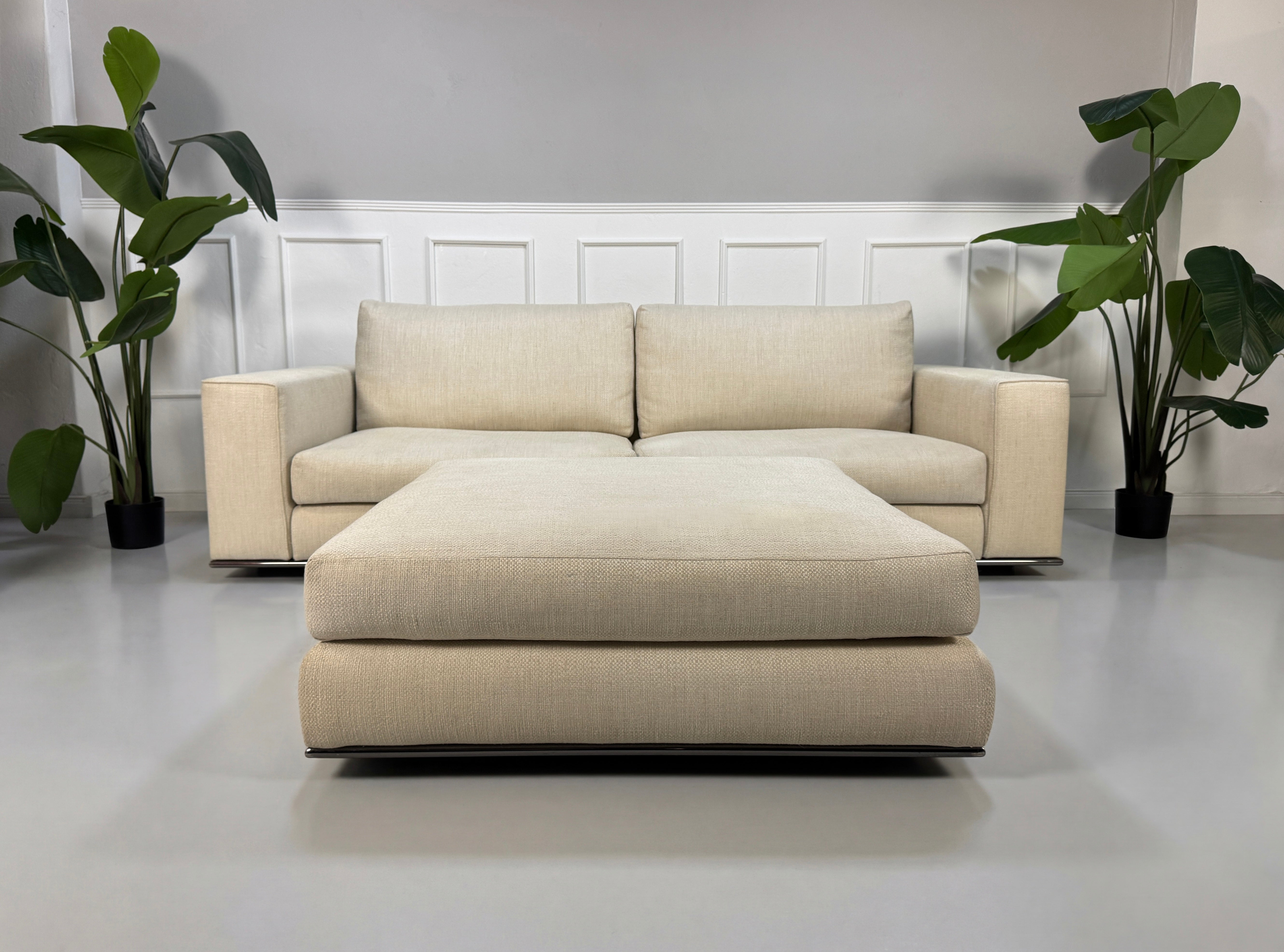 Gebrauchtes beiges Minotti Hamilton Designer Stoff Sofa mit Hocker vor einer Wand, stilvoll und modern eingerichtet.