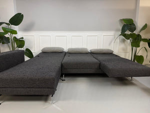 Gebrauchtes Brühl Moule Designer Stoff Sofa in der Farbe Grau vor einer Wand, stilvoll und modern eingerichtet.