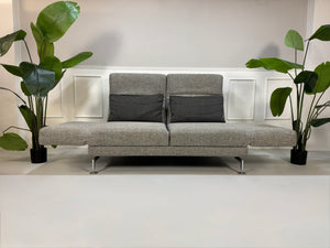 Gebrauchtes Brühl Moule Designer Stoff Sofa in der Farbe Grau vor einer Wand, stilvoll und modern eingerichtet.