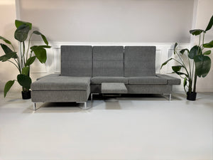 Gebrauchtes Brühl Tomo Designer Stoff Sofa in der Farbe Grau vor einer Wand, stilvoll und modern eingerichtet.