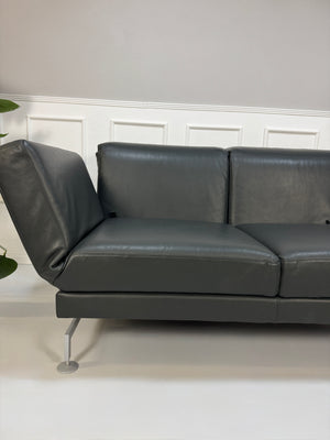 Gebrauchtes Brühl Moule Designer Leder Sofa in der Farbe Grau vor einer Wand, stilvoll und modern eingerichtet.
