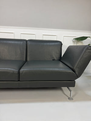 Gebrauchtes Brühl Moule Designer Leder Sofa in der Farbe Grau vor einer Wand, stilvoll und modern eingerichtet.