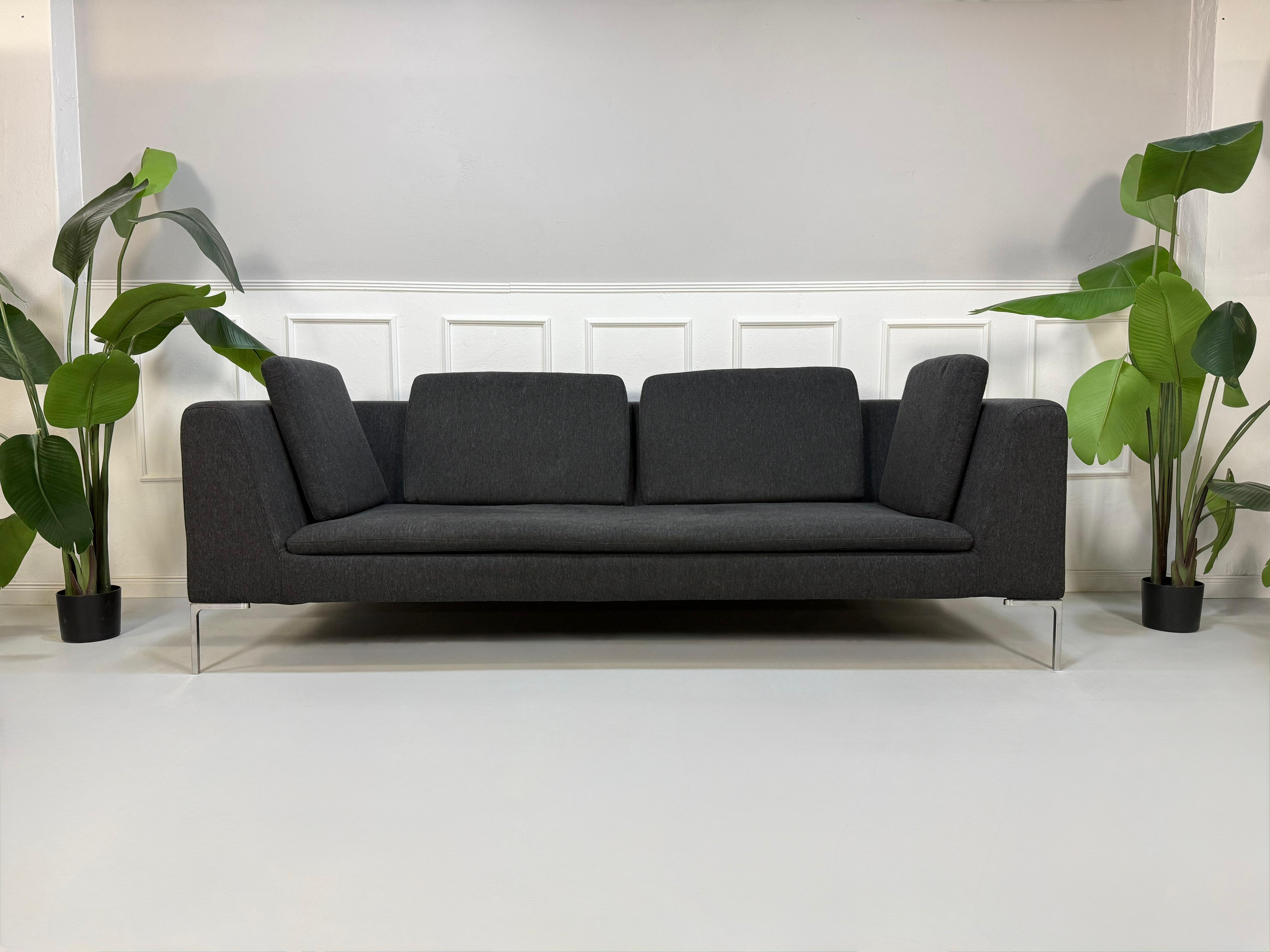 Refurbished graues B&B Italia Charles Designer Stoff Sofa vor einer Wand, stilvoll und modern eingerichtet.