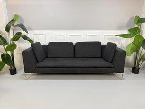 Refurbished graues B&B Italia Charles Designer Stoff Sofa vor einer Wand, stilvoll und modern eingerichtet.