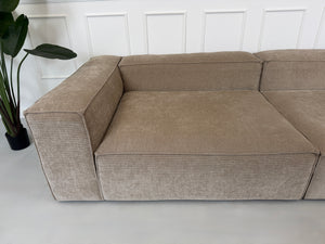 Erneuertes beiges Bolia Cosima Designer Cord Sofa vor einer Wand, stilvoll und modern eingerichtet.