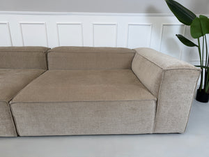 Erneuertes beiges Bolia Cosima Designer Cord Sofa vor einer Wand, stilvoll und modern eingerichtet.