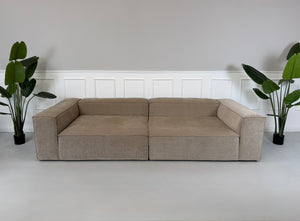 Erneuertes beiges Bolia Cosima Designer Cord Sofa vor einer Wand, stilvoll und modern eingerichtet.